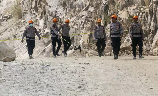 An Indonesian police officer holds a K9 unit search dog as they continue to search for victims at the site of a collapsed natural stones quarry in Cirebon district, West Java province, Indonesia, Saturday, May 31, 2025.(AP Photo/Okri Riyana)