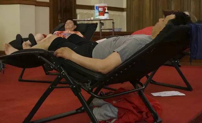 Juan Carlos Toapanta, foreground, and Martha Dominguez, background, receive acupuncture treatments in the sanctuary of St. Paul’s-San Pablo Lutheran Church, which recently added wellness sessions as part of its migrant ministry, in Minneapolis, Sunday, April 27, 2025. (AP Photo/Giovanna Dell’Orto)