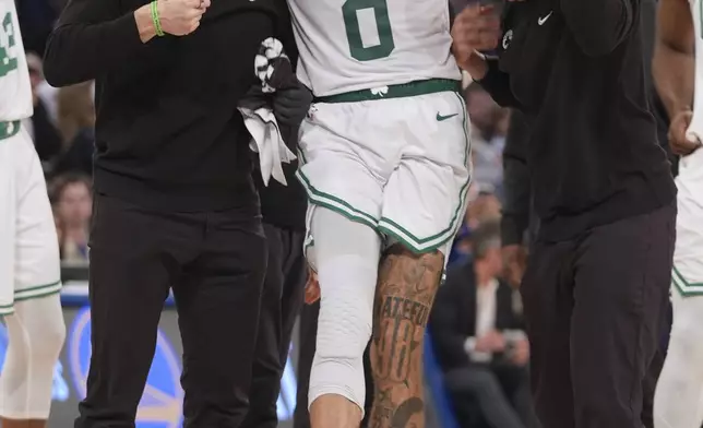 Trainers help Boston Celtics' Jayson Tatum (0) off the court after he was injured during the second half of Game 4 in the Eastern Conference semifinals of the NBA basketball playoffs against the New York Knicks Monday, May 12, 2025, in New York. (AP Photo/Frank Franklin II)