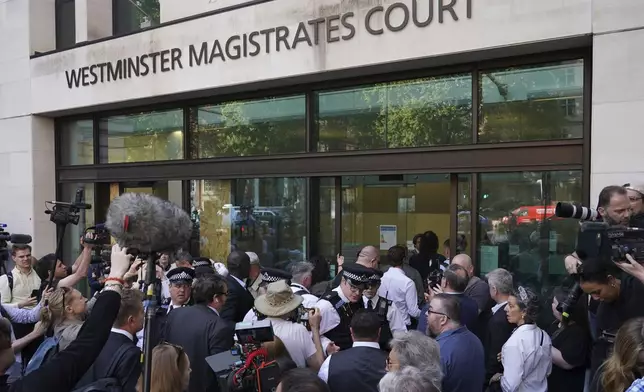 Russell Brand escorted by police and surrounded by the media arrives at Westminster Magistrates' court in London, Friday, May 2, 2025, where he faces, rape and sexual assault charges involving four women. (AP Photo/Alberto Pezzali)