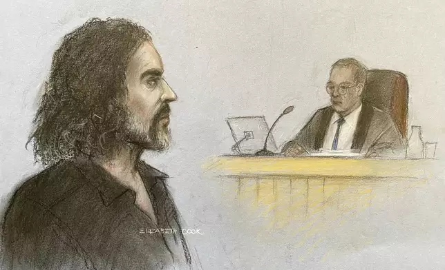 This court artist drawing by Elizabeth Cook shows Russell Brand appearing in the dock at Westminster Magistrates' Court, London, Friday, May 2, 2025, where he is charged with with one count each of rape, indecent assault and oral rape, as well as two counts of sexual assault, relating to four separate women. (Elizabeth Cook/PA via AP)