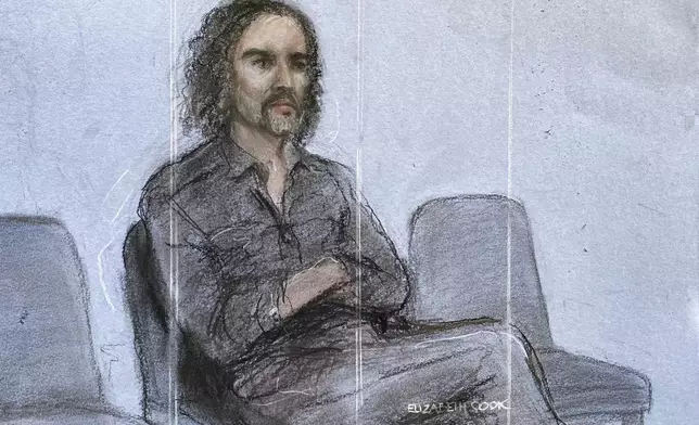 This court artist drawing by Elizabeth Cook shows Russell Brand appearing in the dock at Westminster Magistrates' Court, London, Friday, May 2, 2025, where he is charged with with one count each of rape, indecent assault and oral rape, as well as two counts of sexual assault, relating to four separate women. (Elizabeth Cook/PA via AP)