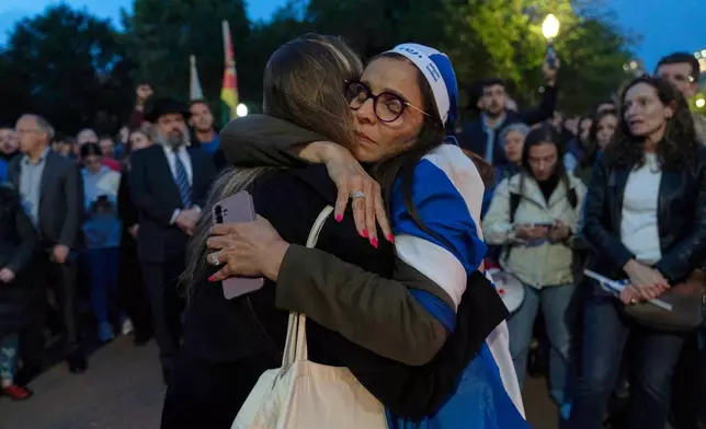 People embrace as they gather to light candles in a makeshift memorial to honor Yaron Lischinsky and Sarah Milgrim who were killed as they left an event at the Capital Jewish Museum in Washington, during a candlelight vigil outside of the White House in Washington, Thursday, May 22, 2025. (AP Photo/Jose Luis Magana)