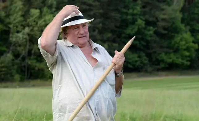FILE - French actor Gerard Depardieu holds a hand scythe in the presidential residence of Ozerny, outside Minsk, Belarus, Wednesday, July 22, 2015. (Andrei Stasevich/BelTA Photo via AP)