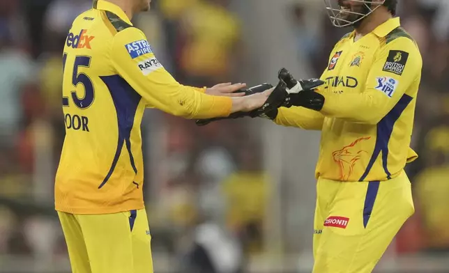 Chennai Super Kings' Noor Ahmad, left, celebrates the wicket of Gujarat Titans' Arshad Khan with captain Mahendra Singh Dhoni during the Indian Premier League cricket match between Gujarat Titans and Chennai Super Kings at Narendra Modi Stadium in Ahmedabad, India, Sunday, May 25, 2025. (AP Photo/Ajit Solanki)