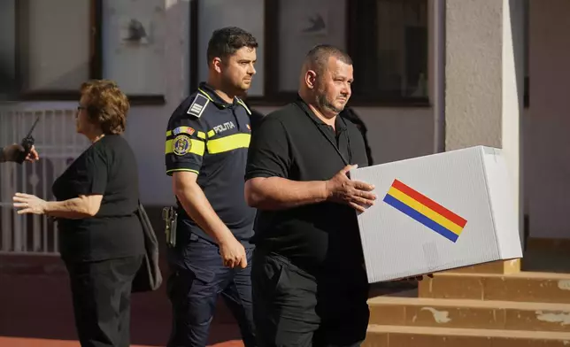 An election official carries a mobile ballot box outside a polling station during the first round of the presidential election redo in Bucharest, Romania, Sunday, May 4, 2025. (AP Photo/Vadim Ghirda)