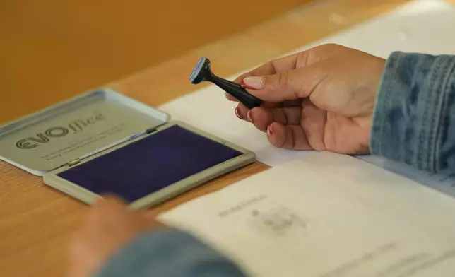An election official holds a voting stamp during the first round of the presidential election redo in Bucharest, Romania, Sunday, May 4, 2025. (AP Photo/Vadim Ghirda)