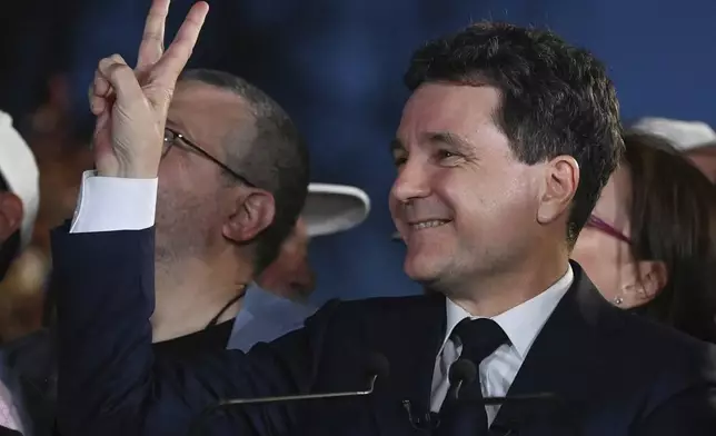 Presidential candidate Nicusor Dan flashes a victory sign after polls closed in the first round of the country's presidential election redo in Bucharest, Romania, Sunday, May 4, 2025. (AP Photo/Eduard Vinatoru)