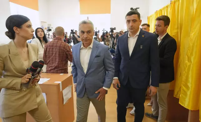 Calin Georgescu, winner of the first round of last year's annulled election, center left, and Presidential candidate George Simion exit after casting their votes in the first round of the presidential election redo in Bucharest, Romania, Sunday, May 4, 2025. (AP Photo/Vadim Ghirda)