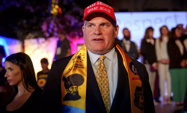 U.S. activist Brian Brown stands as supporters of presidential candidate George Simion celebrate the exit poll results at the headquarters of the Alliance for the Unity of Romanians (AUR) after polls closed for the first round of the country's presidential election redo in Bucharest, Romania, Sunday, May 4, 2025. (AP Photo/Andreea Alexandru)