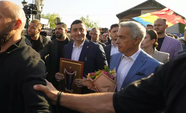 Presidential candidate George Simion, left, holds a religious icon as he walks with Calin Georgescu, winner of the first round of last year's annulled election, after casting their votes in the first round of the presidential election redo in Bucharest, Romania, Sunday, May 4, 2025. (AP Photo/Vadim Ghirda)
