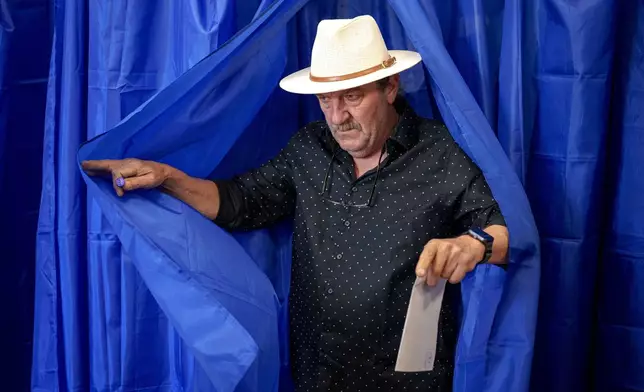 A man exits a voting booth before casting his vote in the first round of the presidential election redo in Bucharest, Romania, Sunday, May 4, 2025. (AP Photo/Andreea Alexandru)
