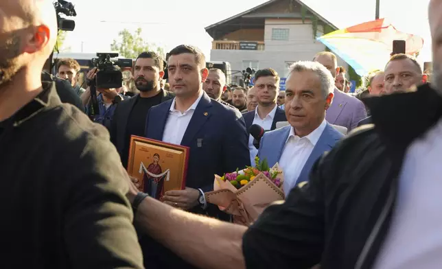 Presidential candidate George Simion, left, holds a religious icon as he walks with Calin Georgescu, winner of the first round of last year's annulled election, after they casted their votes in the first round of the presidential election redo in Bucharest, Romania, Sunday, May 4, 2025. (AP Photo/Vadim Ghirda)