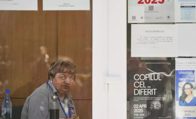 A high school security employee looks at the media waiting outside, at a polling station during the first round of the presidential election redo in Bucharest, Romania, Sunday, May 4, 2025. (AP Photo/Vadim Ghirda)