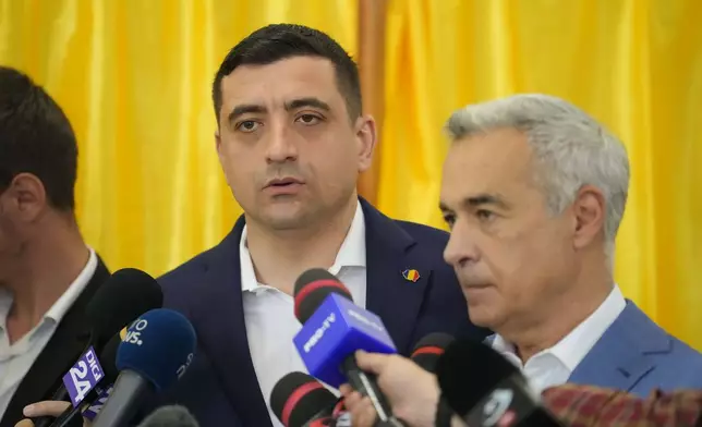Presidential candidate George Simion, left, speaks to media alongside Calin Georgescu, winner of the first round of last year's annulled election, during first round of the presidential election redo in Bucharest, Romania, Sunday, May 4, 2025. (AP Photo/Vadim Ghirda)