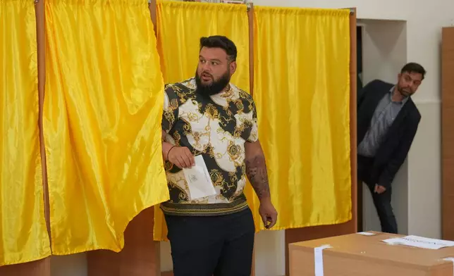 A man exits a voting booth before casting his vote in the first round of the presidential election redo in Bucharest, Romania, Sunday, May 4, 2025. (AP Photo/Vadim Ghirda)