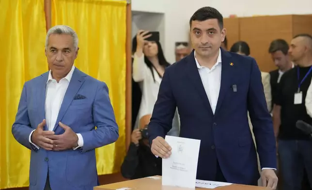 Presidential candidate George Simion, right, casts his vote next to Calin Georgescu, winner of the first round of last year's annulled election, during the first round of the presidential election redo in Bucharest, Romania, Sunday, May 4, 2025. (AP Photo/Vadim Ghirda)