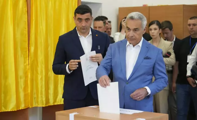 Calin Georgescu, winner of the first round of last year's annulled election, right, casts his vote in the first round of the presidential election redo as Presidential candidate George Simion, left, watches, in Bucharest, Romania, Sunday, May 4, 2025. (AP Photo/Vadim Ghirda)