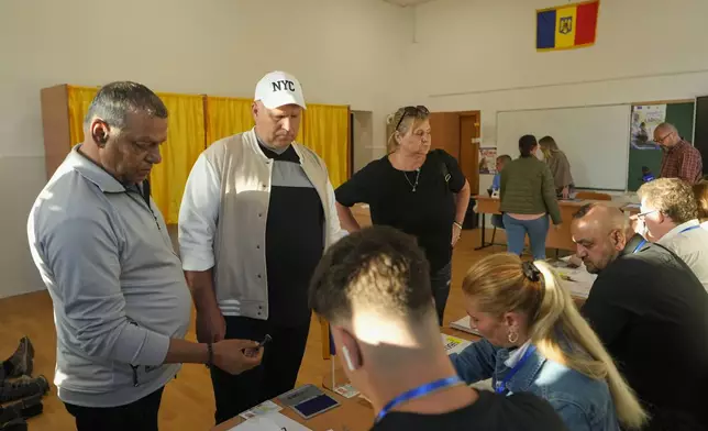 People register before voting in the first round of the presidential election redo in Bucharest, Romania, Sunday, May 4, 2025. (AP Photo/Vadim Ghirda)