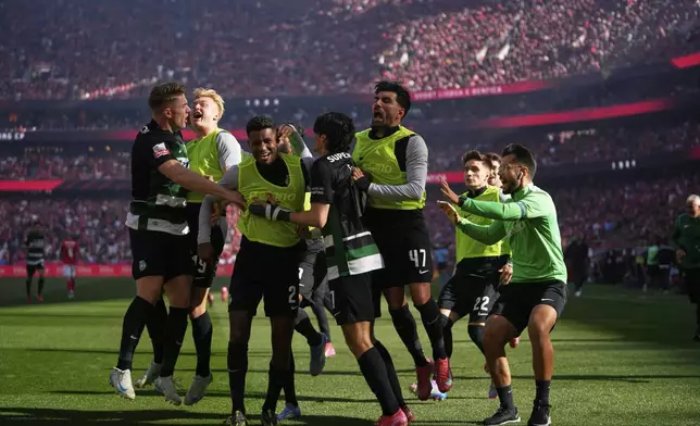 Sporting's Francisco Trincao, center, is congratulated after scoring his side's opening goal during a Portuguese league soccer match between SL Benfica and Sporting CP at the Luz stadium in Lisbon, Saturday, May 10, 2025. (AP Photo/Armando Franca)