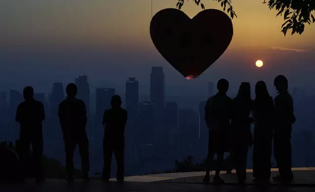 People enjoy the sunset scenery over the high-rise buildings in southwest China's Chongqing Municipality, Monday, May 19, 2025. (AP Photo/Andy Wong)