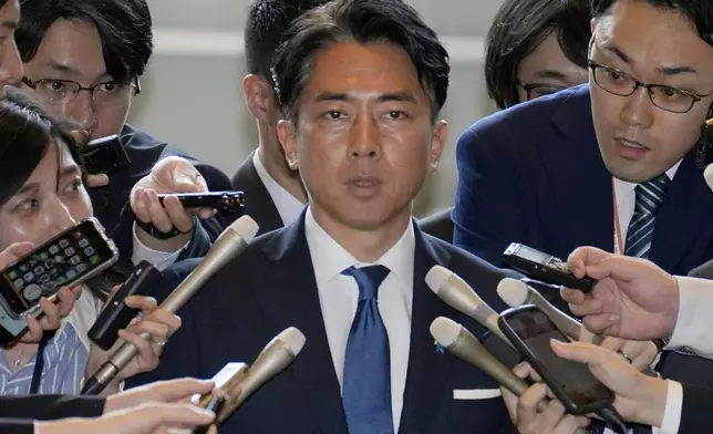 Former Environment Minister Shinjiro Koizumi, center, is surrounded by reporters at the prime minister's office in Tokyo Wednesday, May 21, 2025. (Kyodo News via AP)