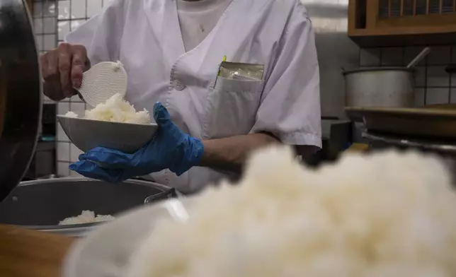 An employee prepares a bowl of rice at a restaurant in Tokyo, Thursday, May 22, 2025. (AP Photo/Louise Delmotte)