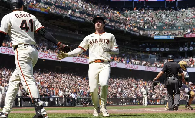 San Francisco Giants' Patrick Bailey, right, celebrates with Wilmer Flores, left, after scoring against the Athletics on Heliot Ramos' single during the eighth inning of a baseball game Sunday, May 18, 2025, in San Francisco. (AP Photo/Godofredo A. Vásquez)