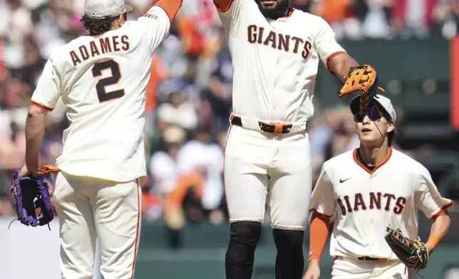 San Francisco Giants shortstop Willy Adames (2) and left fielder Heliot Ramos, center, celebrate after the team's victory over the Athletics in a baseball game Sunday, May 18, 2025, in San Francisco. (AP Photo/Godofredo A. Vásquez)