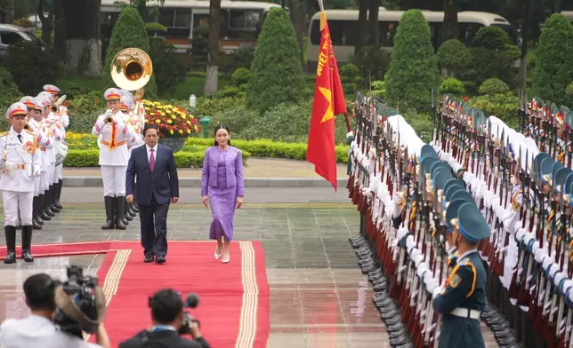 Vietnamese Prime Minister Pham Minh Chinh, center left, and Thai Prime Minister Paetongtarn Shinawatra, center right, review honor guards during a welcome ceremony in Hanoi, Vietnam Friday, May 16, 2025. (AP Photo/Hau Dinh)