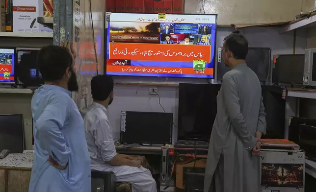 Shopkeepers watch a news channel telecasting ongoing military tension between Pakistan and India, at a shop in Peshawar, Pakistan, Saturday, May 10, 2025. (AP Photo/Muhammad Sajjad)