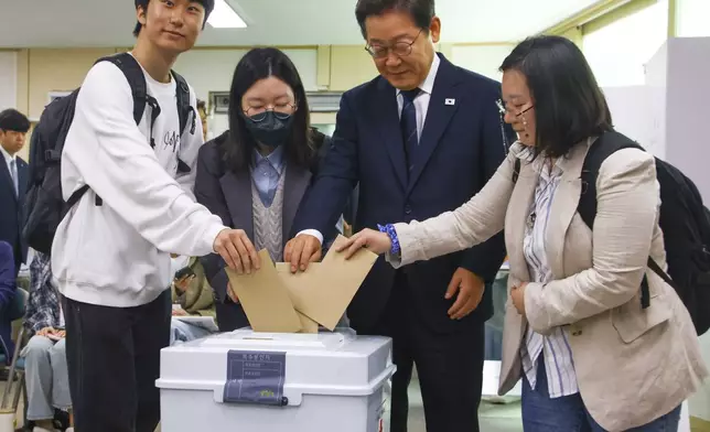 South Korean Democratic Party's presidential candidate Lee Jae-myung, second from right, and young people cast their early votes for the June 3 presidential election at a polling station in Seoul, South Korea, Thursday, May 29, 2025. (Yonhap via AP)