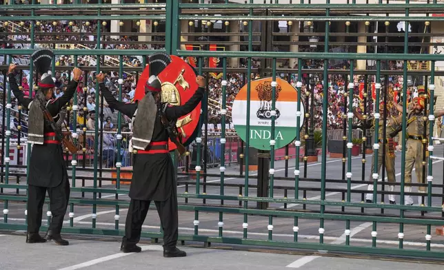 Pakistan's Rangers soldiers, left, and Indian Border Security Forces soldiers, behind the gate, gesture to each other during a daily closing ceremony at the Wagah, a joint post on the Pakistan and India border, near Lahore, Pakistan, Saturday, May 3, 2025. (AP Photo/K.M. Chaudary)