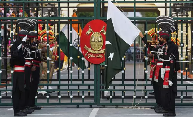 Pakistan's Rangers soldiers, in black, and Indian Border Security Forces soldiers, lower their flags during a daily closing ceremony at the Wagah, a joint post on the Pakistan and India border, near Lahore, Pakistan, Saturday, May 3, 2025. (AP Photo/K.M. Chaudary)