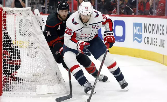Washington Capitals' Nic Dowd (26) controls the puck in front of Carolina Hurricanes' Jaccob Slavin (74) during the first period of Game 3 of an NHL hockey Semi-final round playoff series in Raleigh, N.C., Saturday, May 10, 2025. (AP Photo/Karl DeBlaker)