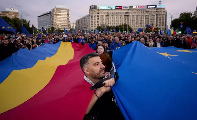 Demonstrators hold large Romanian and European Union flags during a pro-EU rally ahead of the second round of the presidential election redo in Bucharest, Romania, Friday, May 9, 2025. (AP Photo/Andreea Alexandru)