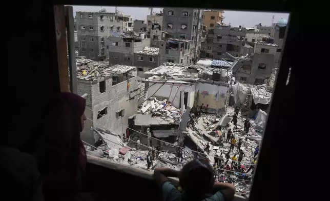 A child and a woman look as Palestinians search the rubble of a house targeted by an Israeli army strike that killed killing at least five members of the Abu Sahloul family in Khan Younis, in the southern Gaza Strip, Thursday, May 1, 2025. (AP Photo/Abdel Kareem Hana)