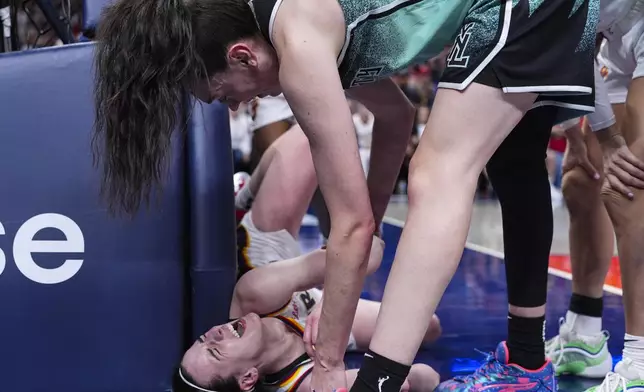 New York Liberty forward Breanna Stewart, top, checks on Indiana Fever guard Caitlin Clark (22) after contract on a shot in the second half of a WNBA basketball game in Indianapolis, Saturday, May 24, 2025. (AP Photo/Michael Conroy)