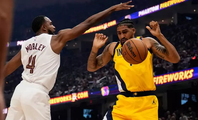 Cleveland Cavaliers forward Evan Mobley (4) knocks the ball away from Indiana Pacers forward Obi Toppin, right, in the first half of Game 1 in the Eastern Conference semifinals of the NBA basketball playoffs Sunday, May 4, 2025, in Cleveland. (AP Photo/Sue Ogrocki)
