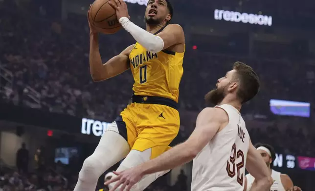 Indiana Pacers' Tyrese Haliburton (0) goes to the basket in front of Cleveland Cavaliers' Dean Wade (32) in the first half of Game 1 in the Eastern Conference semifinals of the NBA basketball playoffs Sunday, May 4, 2025, in Cleveland. (AP Photo/Sue Ogrocki)