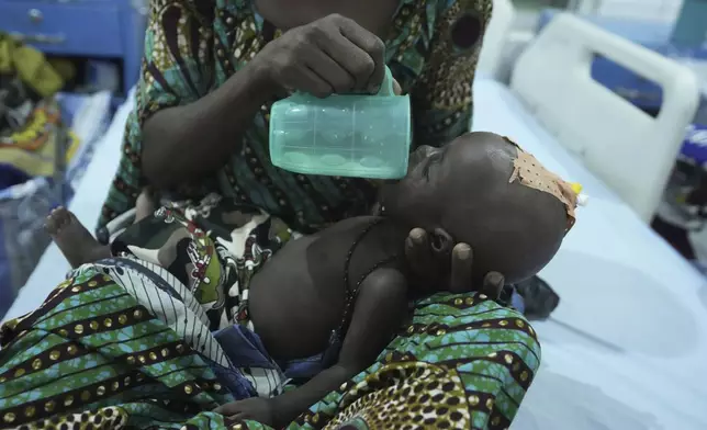 A mother feeds her malnourished child with milk at the stablization centre in Maiduguri, northeastern, Nigeria, Thursday, May 1, 2025. (AP Photo/Sunday Alamba)