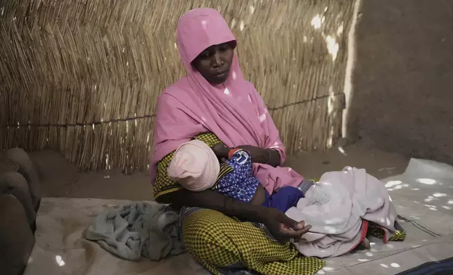 Yagana Bulama, a 40 years old woman breast feed her surviving infant under the dappled light of a thatched shelter in Dikwa, northeastern, Nigeria, Tuesday, April 29, 2025. (AP Photo/Sunday Alamba)