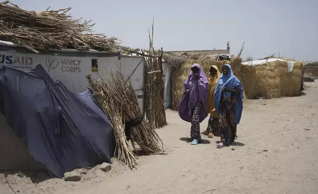 Women walk past a USAID tent at the internal displaced peoples camp in Dikwa, northeastern, Nigeria, Tuesday, April 29, 2025. (AP Photo/Sunday Alamba)