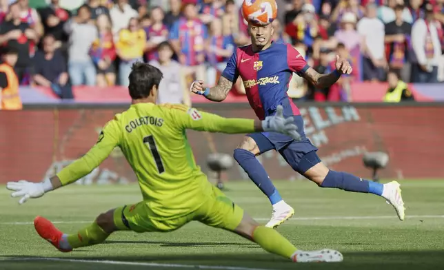 Barcelona's Raphinha shoots by Real Madrid's goalkeeper Thibaut Courtois during the La Liga soccer match between Barcelona and Real Madrid in Barcelona, Spain, Sunday, May 11, 2025. AP Photo/Joan Monfort)