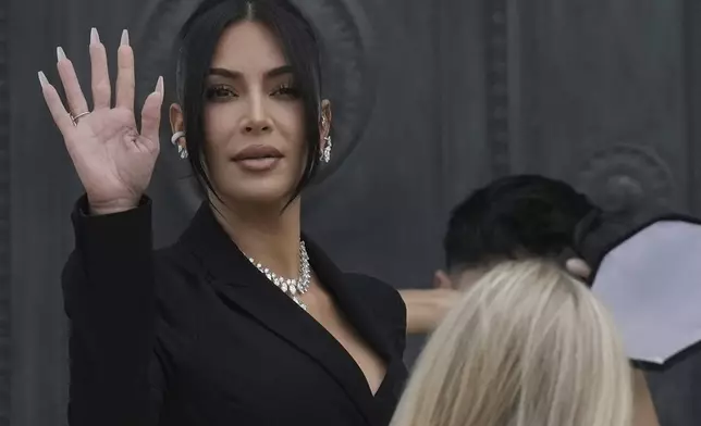 Kim Kardashian waves as she arrives to testify regarding a robbery of millions of dollars in jewels from her Paris hotel room in 2016, in Paris, Tuesday, May 13, 2025. (AP Photo/Aurelien Morissard)