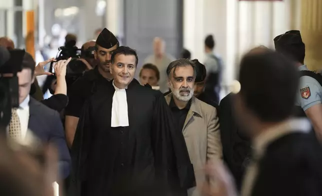 Abderrahmane Ouatiki, center right, who was working as a hotel receptionist, is accompanied by his lawyer Mohand Ouidja, center left, as they arrive for the trial of the 2016 armed robbery of Kim Kardashian, at the palace of justice, Tuesday, May 13, 2025 in Paris. (AP Photo/Aurelien Morissard)