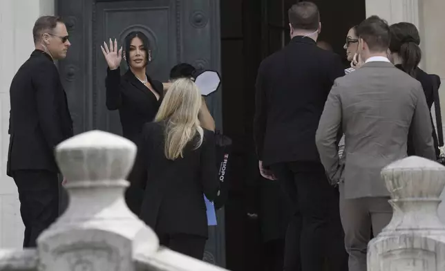 Kim Kardashian waves as she arrives to testify regarding a robbery of millions of dollars in jewels from her Paris hotel room in 2016, in Paris, Tuesday, May 13, 2025. (AP Photo/Aurelien Morissard)