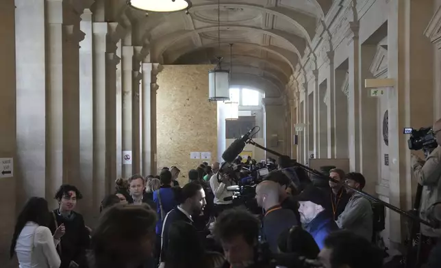 Media and others wait outside the palace of justice ahead of the trial for the robbery of millions of dollars in jewels from the Paris hotel room of Kim Kardashian in 2016, on Tuesday, May 13, 2025 in Paris. (AP Photo/Christophe Ena)