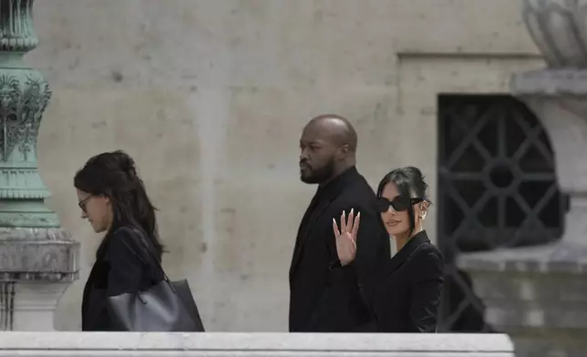 Kim Kardashian, right, waves as she arrives to testify regarding a robbery of millions of dollars in jewels from her Paris hotel room in 2016, in Paris, Tuesday, May 13, 2025. (AP Photo/Aurelien Morissard)