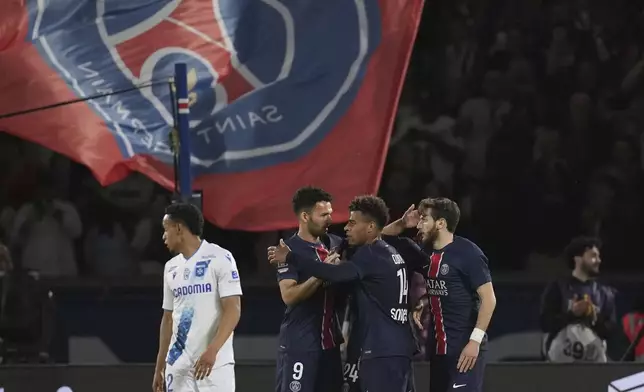 PSG's Khvicha Kvaratskhelia, right is congratulated by team mates after scoring his side's third goal during the French League One soccer match between Paris Saint-Germain and Auxerre at the Parc des Princes stadium in Paris, Saturday, May 17, 2025. (AP Photo/Christophe Ena)